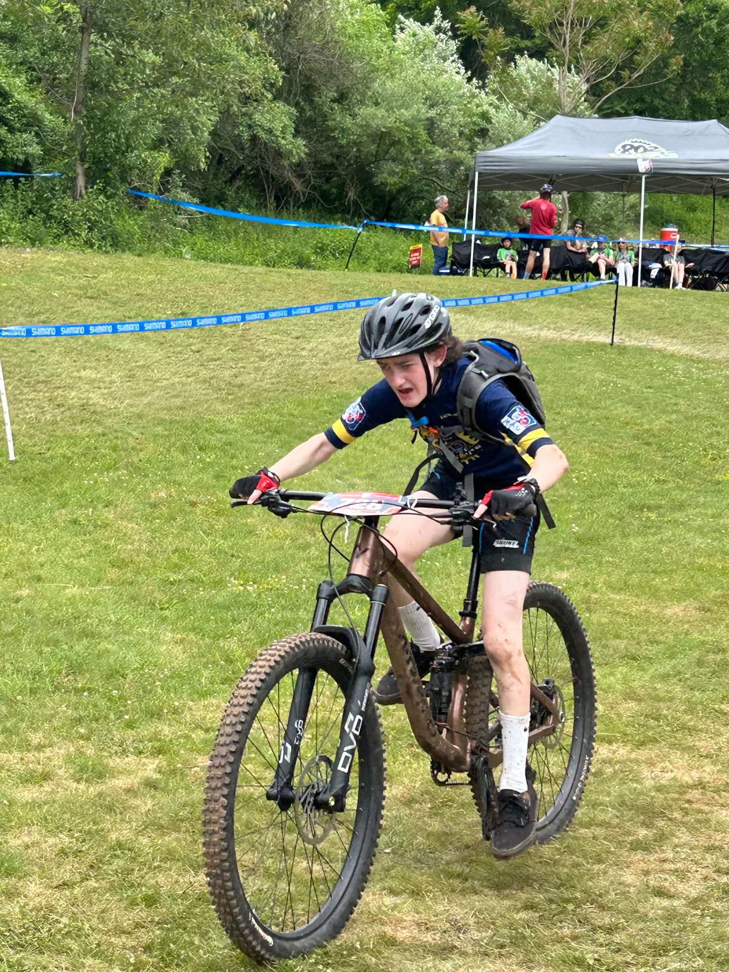 A Shredders rider grinding up a grassy climb on a muddy bike